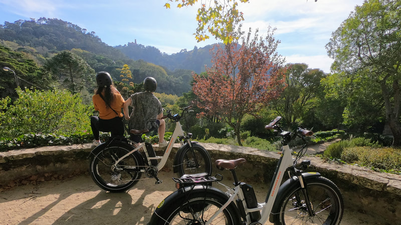 Young couple on an ebike tour enjoying the view of Pena palace in Sintra from a beautiful garden