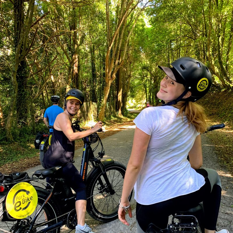 Young ladies on a forest road in Sintra on their ebikes look back