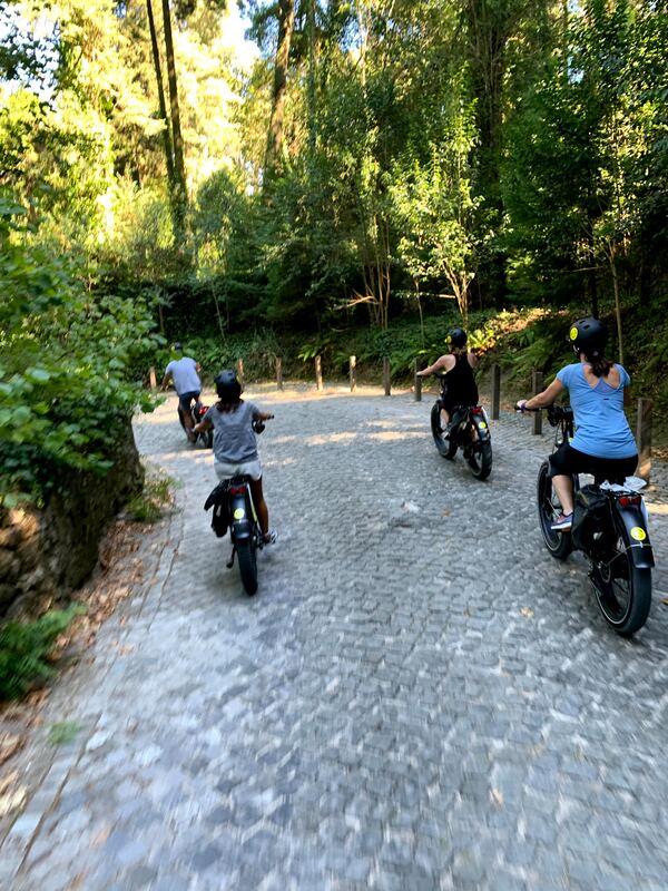 Family cycling on an old cobbled road on fat tire ebikes in Sintra